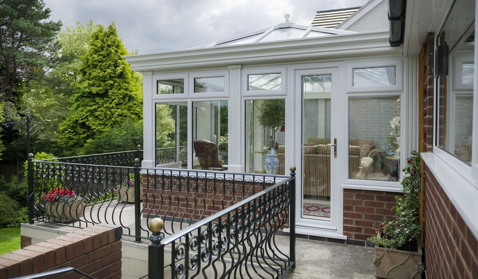 Daytime view of a white orangery and garden landscaping